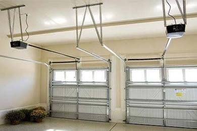 An interior view of a garage showcasing two installed garage doors and their automatic openers by Above The Rest Garage Door in Colorado Springs, CO.