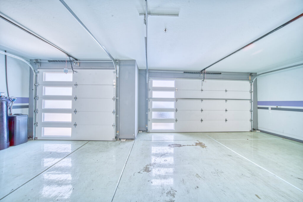 Interior view of a garage featuring two modern white garage doors with frosted windows by Blue Fox Garage Doors in Gilbert, AZ.