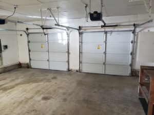Interior view of two newly installed white garage doors with openers by Steadfast Garage Door Services LLC in Federal Way, WA.