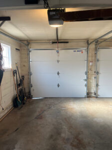 Interior view of a garage showing two white garage doors and openers installed by CCM Overhead Doors in Oklahoma City, OK.