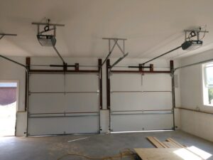 Interior view of a garage showing two white garage doors and openers fully installed by Ken's Overhead Door in Clarksville, TN.