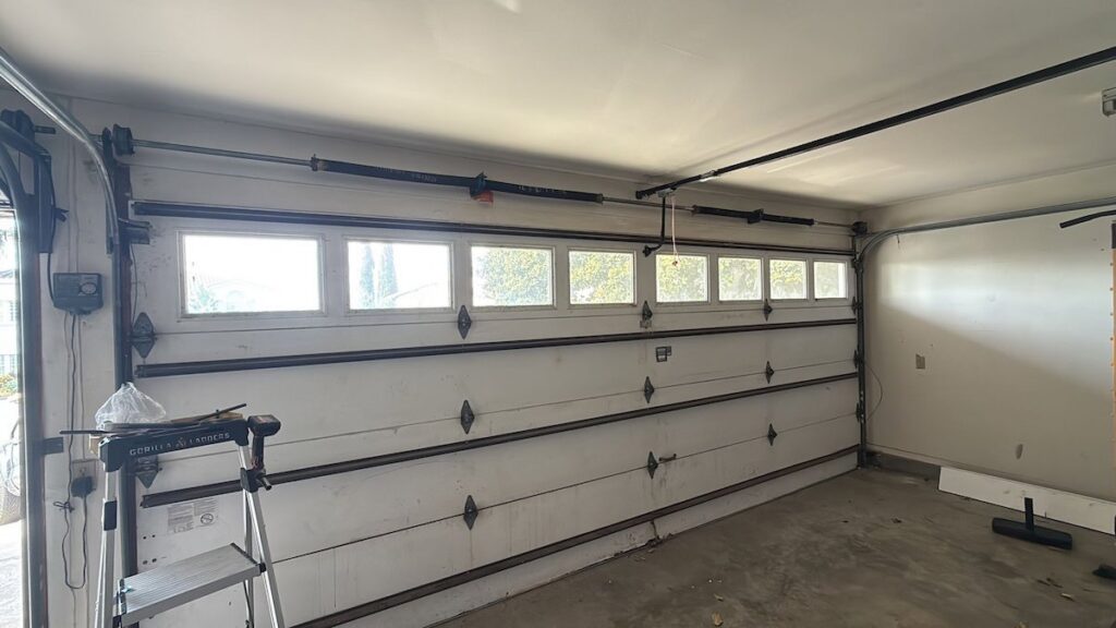 Interior view of a white garage door showing tracks and springs, indicating a job site for Baystate Garage Door in Milton, MA.