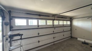 Interior view of a white garage door showing tracks and springs, indicating a job site for Baystate Garage Door in Milton, MA.