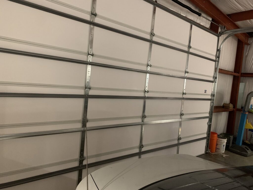 An interior view of a white sectional garage door showing the panels and tracks, installed by Affordable Overhead Garage Door in Modesto, CA