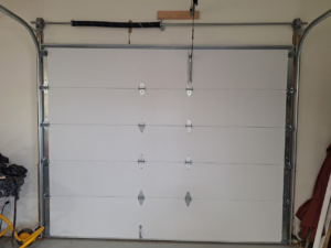 Interior view of a white sectional garage door with visible springs and tracks by Roll-Rite Garage Doors in Denver, CO.