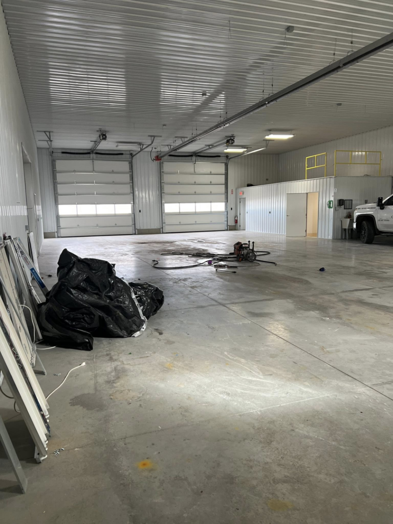 Interior view of a warehouse featuring two white overhead garage doors installed by Tri County Overhead Door Service Inc in New London, WI.
