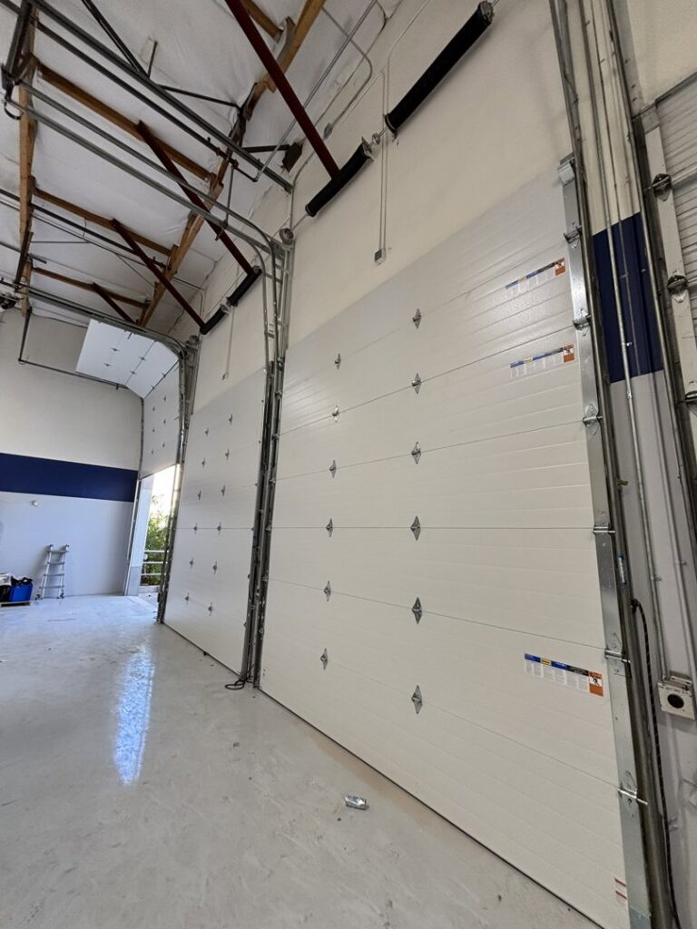 Interior view of multiple white commercial overhead doors installed by Stapley Action Garage Door in Mesa, AZ.