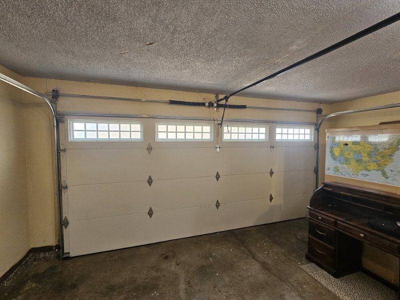 Interior view of a white garage door with top windows and spring mechanism by Total Door Solutions in Yukon, OK