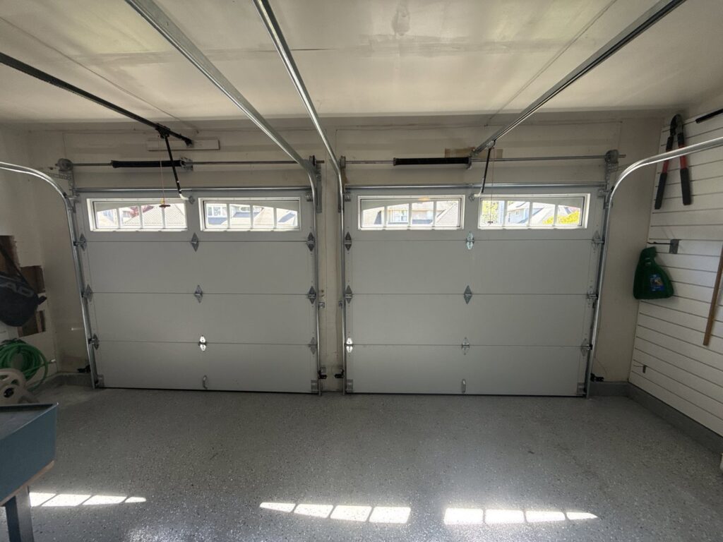 Interior view of two white garage doors, showcasing the tracks and springs, installed by Rainier Garage Door in Bellevue, WA.