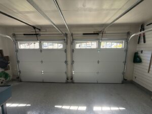 Interior view of two white garage doors, showcasing the tracks and springs, installed by Rainier Garage Door in Bellevue, WA.