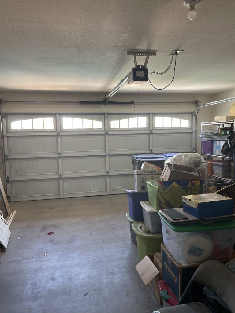 Interior view of a garage with a white panel garage door and opener installed by Blue Fox Garage Doors in Gilbert, AZ.