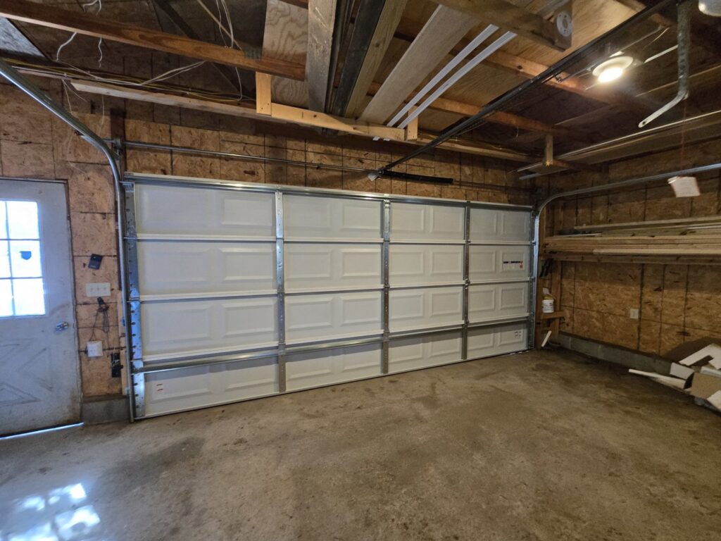 Interior view of a white paneled garage door and its tracks installed by LabraDoor Overhead Services in Eau Claire, WI.