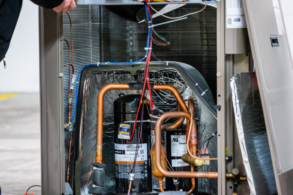 Internal components of an outdoor HVAC unit, showing compressors and copper lines, by KCM Heating & Air Conditioning in Omaha, NE.