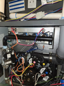 A detailed view of the internal components, wiring, and pipes of an HVAC furnace or air handler by Goodie Heating & Air in Sandy, UT.