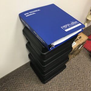 An IPM Technical Manual resting on a stack of black pest bait stations from Perimetek Pest Management in East Syracuse, NY.