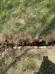Irrigation pipes being installed in a trench in a grassy area by L&L Lawn Care Service in Dothan, AL.