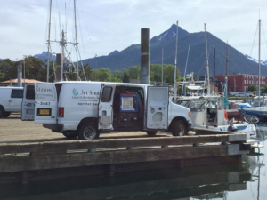 A Jet Steam Carpet Cleaning van with open doors showing equipment, parked by a dock in Sitka, AK.