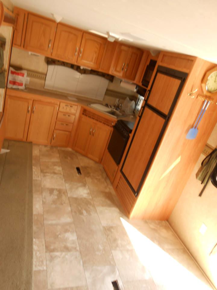 A kitchen area featuring newly installed light brown tile-patterned vinyl flooring by Frosty's Carpet Center, Inc. in Grand Forks, ND.