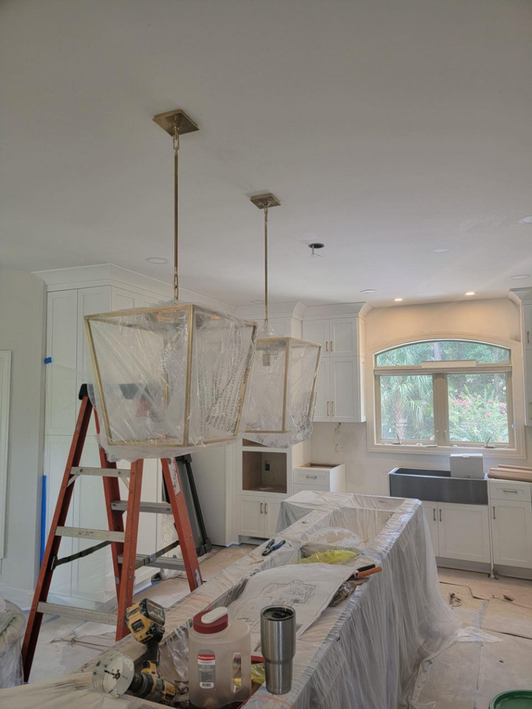Electrician installing pendant lights in a kitchen during construction by D&R Construction & Electrical Services in Summerville, SC.