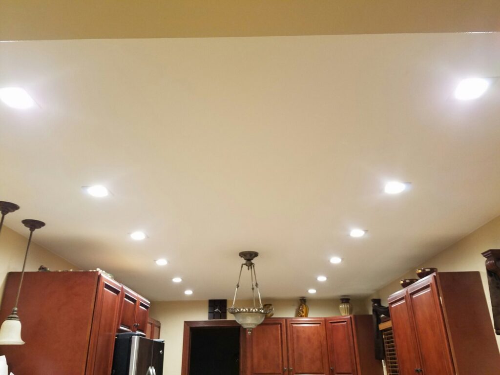 A kitchen featuring extensive recessed lighting and a central chandelier installed by MDEC Electrical & Lighting in Livonia, MI.