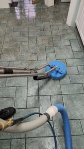 A kitchen tile floor being professionally cleaned with a rotary scrubber by LNC Steam Cleaning in Owasso, OK.