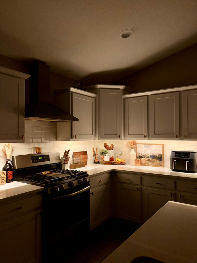A modern kitchen showcasing bright under-cabinet lighting and recessed ceiling lights installed by Woodford Power & Light Co. in Ankeny, IA.