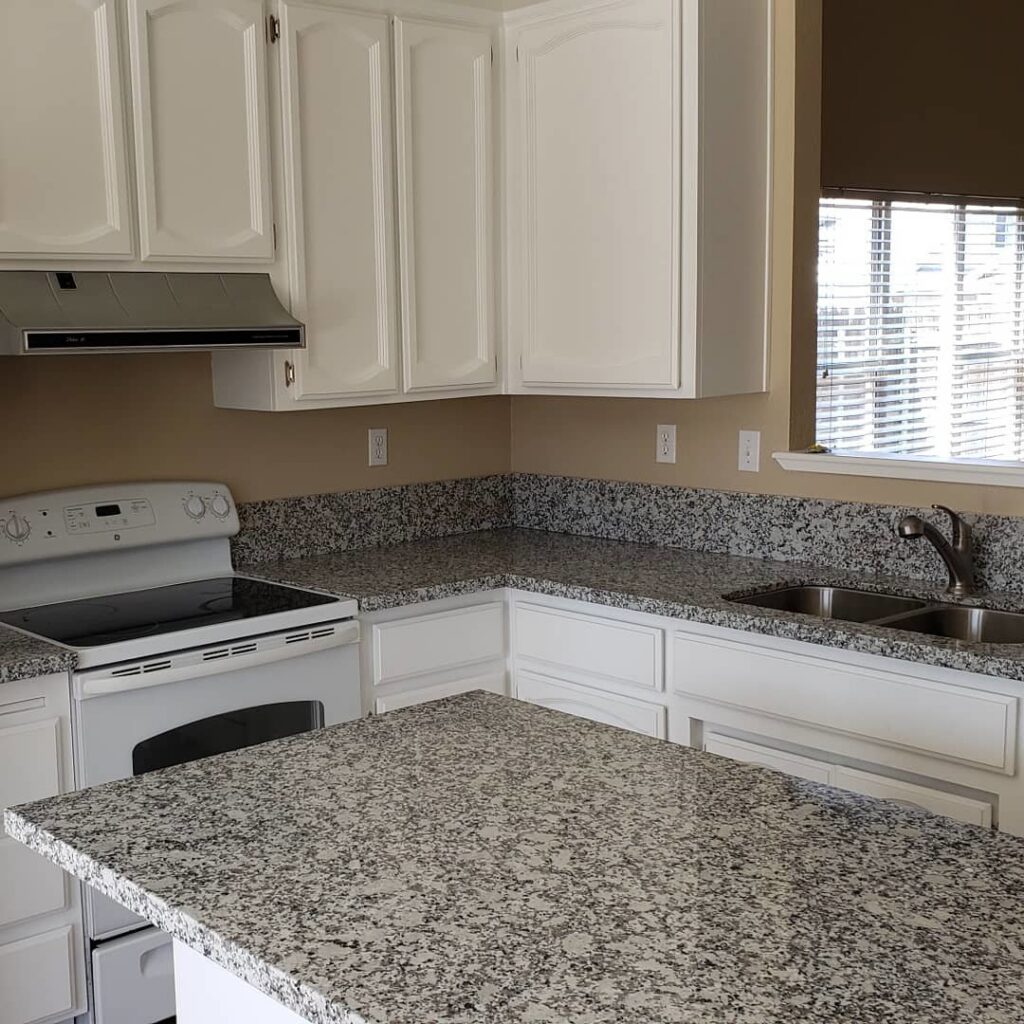 Kitchen with white cabinets, speckled granite countertops, and tile flooring by Sulcas Carpets & more in Elk Grove, CA