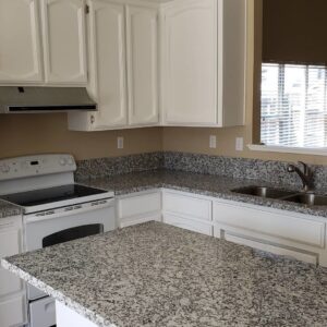 Kitchen with white cabinets, speckled granite countertops, and tile flooring by Sulcas Carpets & more in Elk Grove, CA