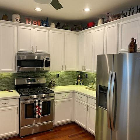 Completed kitchen renovation with white cabinets, green backsplash, and dark wood flooring by Sulcas Carpets & more in Elk Grove, CA