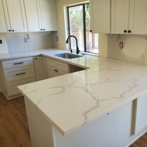 Newly renovated kitchen with white cabinets and light wood-look flooring by Sulcas Carpets & more in Elk Grove, CA