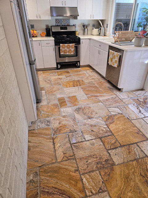 A modern kitchen featuring natural stone tile flooring, a service offered by All American Carpet & Tile in San Diego, CA