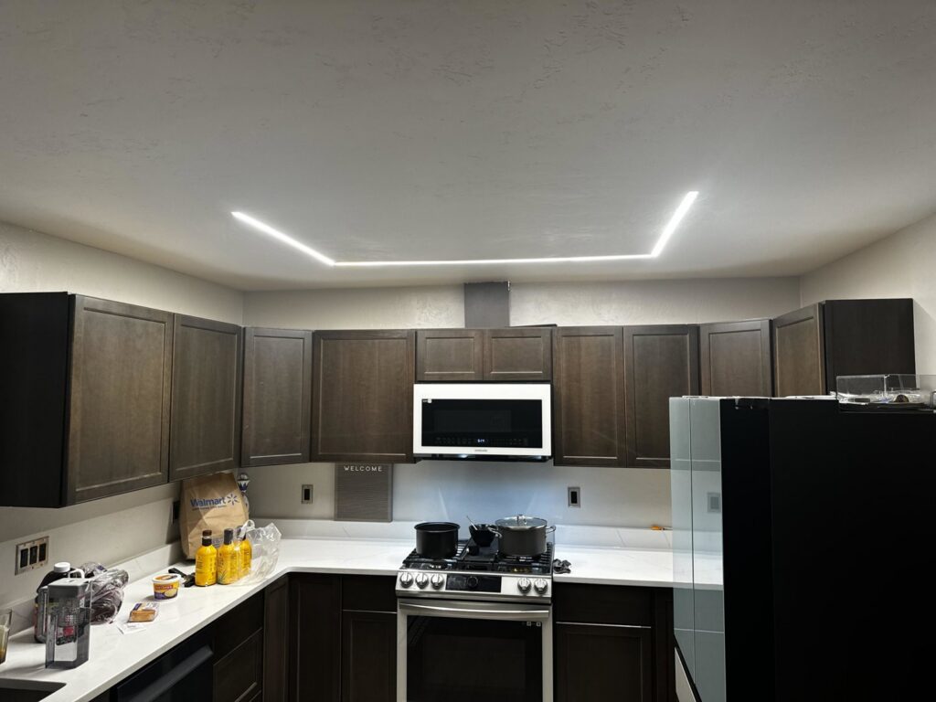 A modern kitchen featuring recessed linear LED lighting installed by Intel-electric in Anchorage, AK
