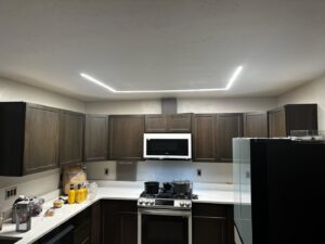 A modern kitchen featuring recessed linear LED lighting installed by Intel-electric in Anchorage, AK