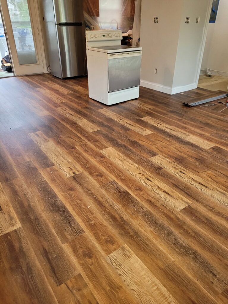 A kitchen area with newly installed wood-look plank flooring by VA Carpet Connection LLC in Chesapeake, VA.