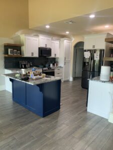A modern kitchen with new grey wood-look tile flooring and a blue island installed by Carpet Direct Brandon Burley in Tulsa, OK.