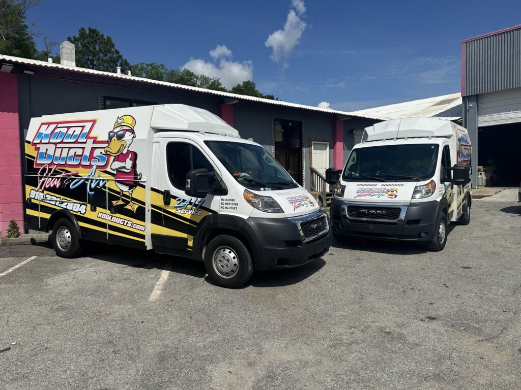 Two Kool Ducts Heat & Air branded service vans parked outside the business location in Wilmington, NC.