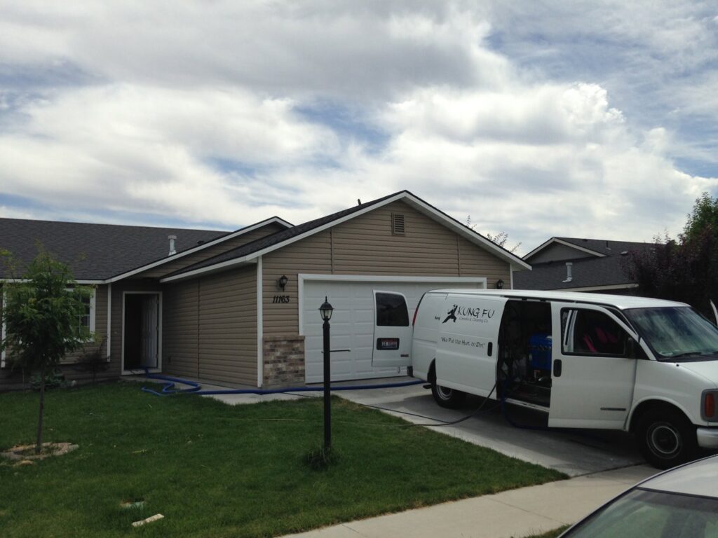 The Kung Fu Carpets and Cleaning Co. service van parked outside a home with hoses running inside for a job in Meridian, ID.