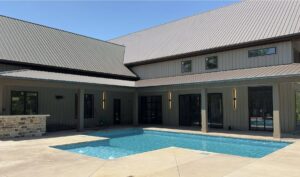 An L-shaped inground pool with light blue water and concrete patio, expertly installed by Riverstone LLC in Bowling Green, KY.