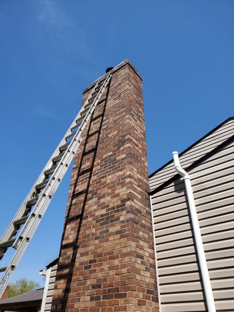 A tall ladder leaning against a brick chimney, ready for service by Clean Sweep Chimney Service in Saint Charles, MO.