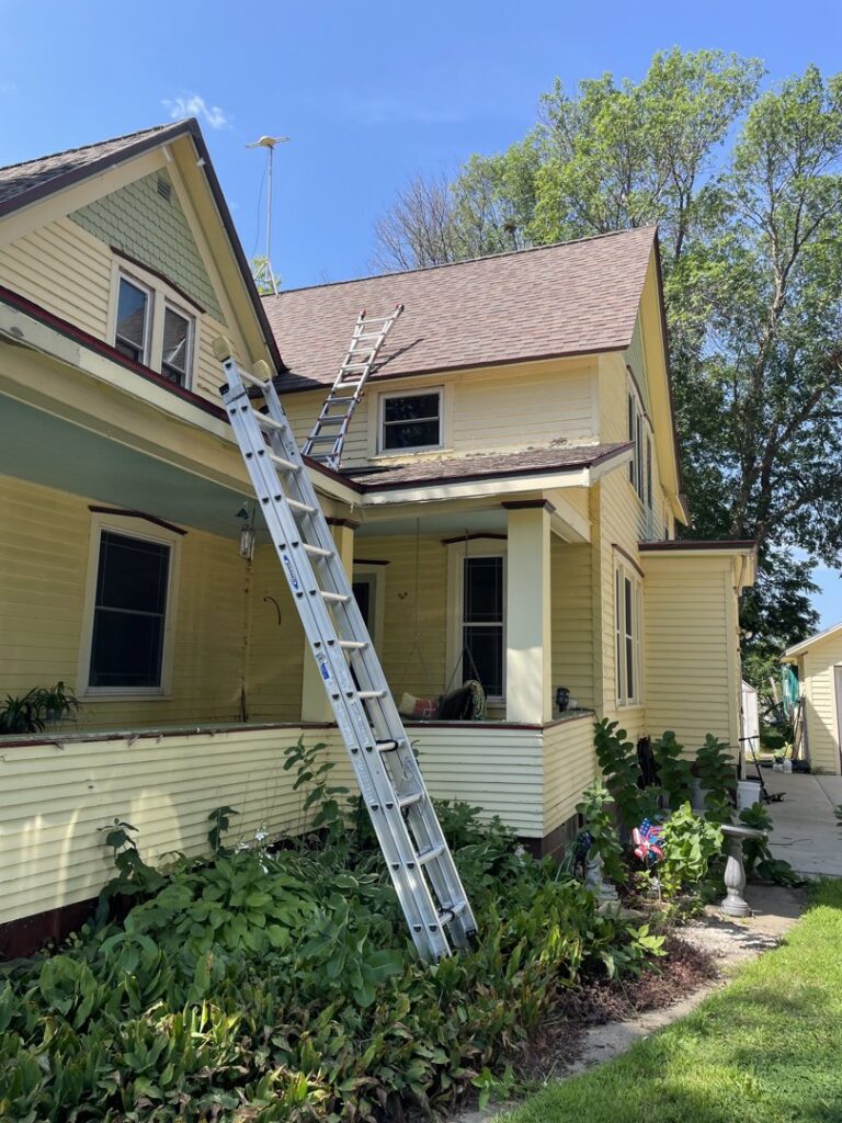 A ladder positioned against a yellow house for roof inspection or wildlife exclusion by Prairie Bat Services, LLC in Sioux Falls, SD.