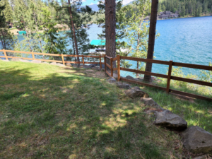 A wooden fence with wire mesh and a gate installed along a lakeside property by EcoGreen Fencing in Coeur d'Alene, ID.
