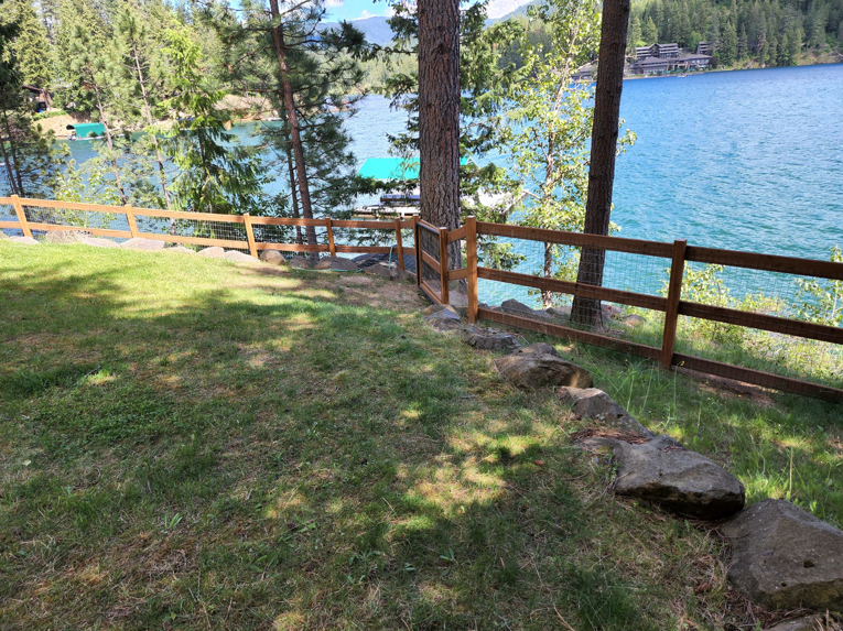 A wooden fence with wire mesh and a gate installed along a lakeside property by EcoGreen Fencing in Coeur d'Alene, ID.