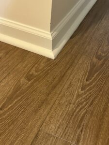 Close-up of new laminate flooring and baseboard installation by Peach Design Inc., a carpet contractor in Atlanta, GA.