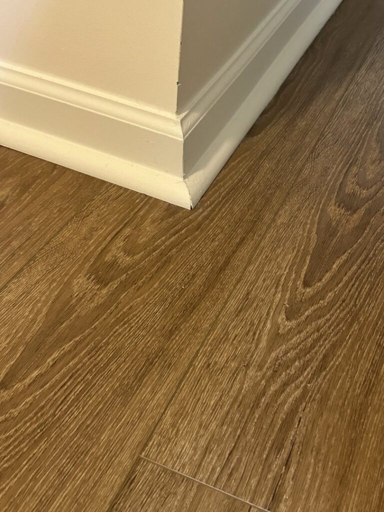 Close-up of new laminate flooring and baseboard installation by Peach Design Inc., a carpet contractor in Atlanta, GA.
