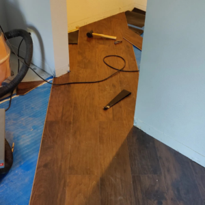 Laminate wood-look flooring installation in progress with tools and blue underlayment by Steam Vs. Soil Carpet Cleaning in San Diego, CA