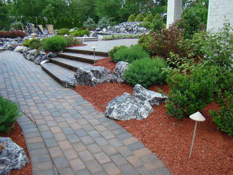 A professionally designed landscape with a paved walkway, steps, and mulched beds by Kustom Lawn Kare LLC in Greenwood, IN.
