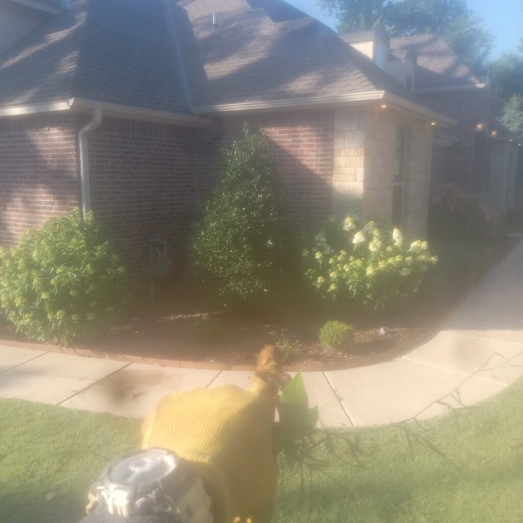 A completed landscape design with fresh mulch and new plants next to a house by A & A Lawn Care Service LLC in Moore, OK.