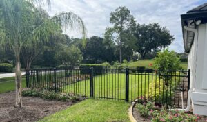 A beautifully landscaped backyard enclosed by a black aluminum fence, expertly installed by Exacta FENCE LLC in Jacksonville, FL.