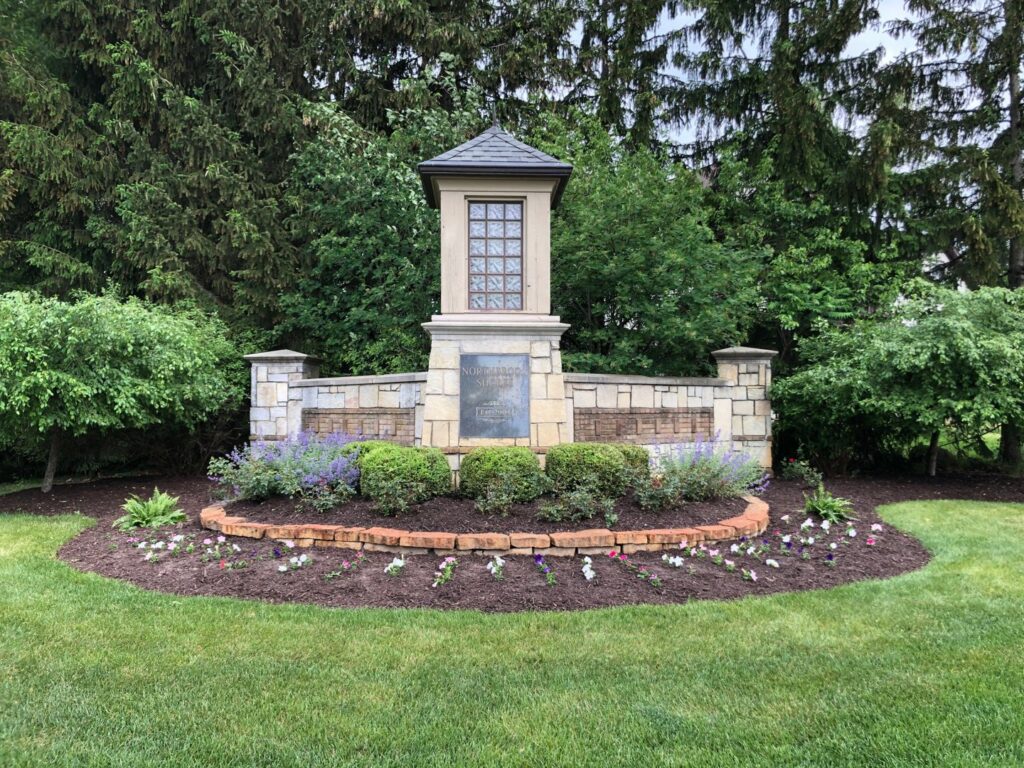 A beautifully landscaped entrance sign with flowers and shrubs, maintained by Roots Lawn Care Solutions in Granger, IN.