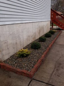 A neatly landscaped garden bed with small bushes and decorative gravel by John's Lawn Care Service's in Saint Petersburg, FL